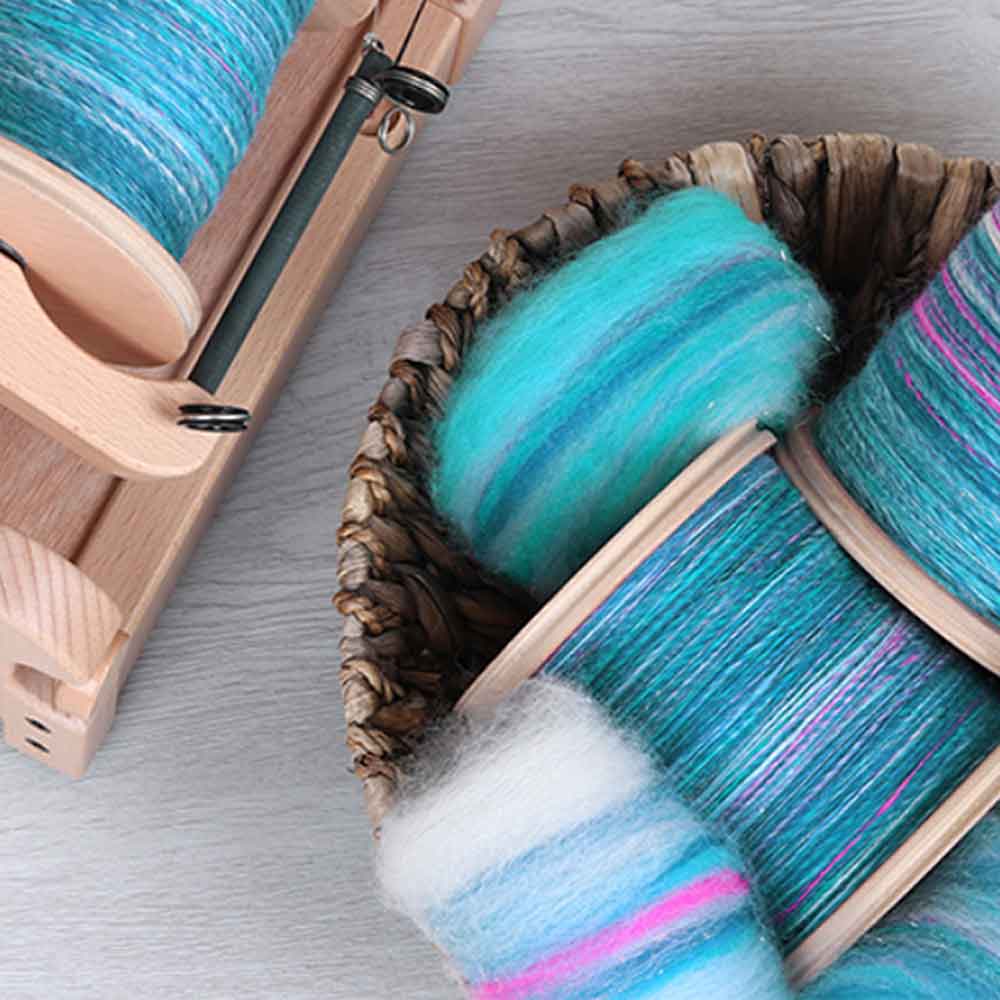 Spinning wheel with flyer and bobbin in the foreground – Tisse et File spinning accessories collection