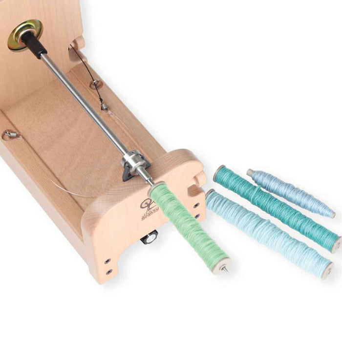 Ashford e-Spinner 3 with Boat Shuttle Bobbin Winder attachment – winding colorful shuttle bobbins on stainless steel spindle.