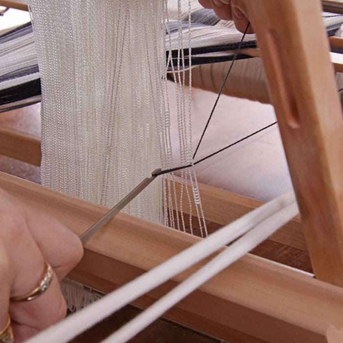 Ashford heddle hook pulling warp threads through the loom