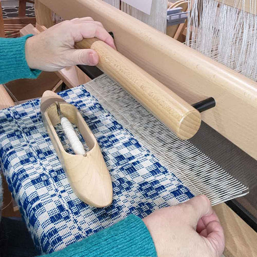 Cours de tissage en personne : mains au métier à cadres avec motif overshot bleu et navette en bois — Tisse et File