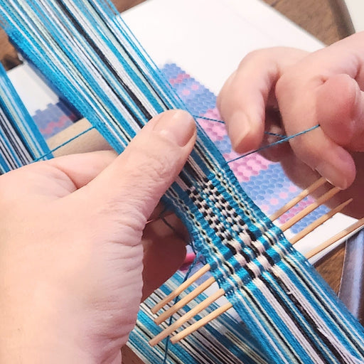 Student weaving an inkle band during a weaving class