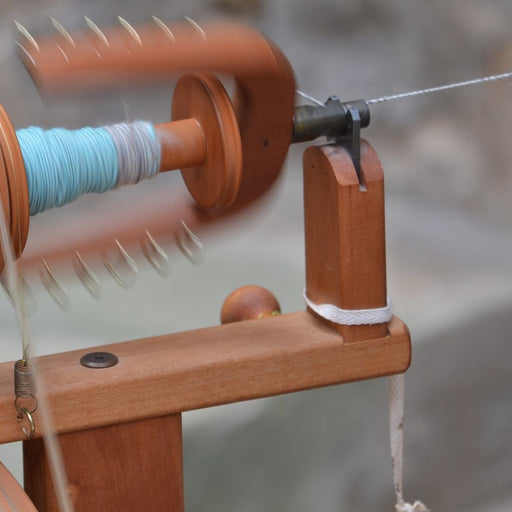 Beginner learning to spin a two-ply yarn on a spinning wheel during a workshop at Tisse et File