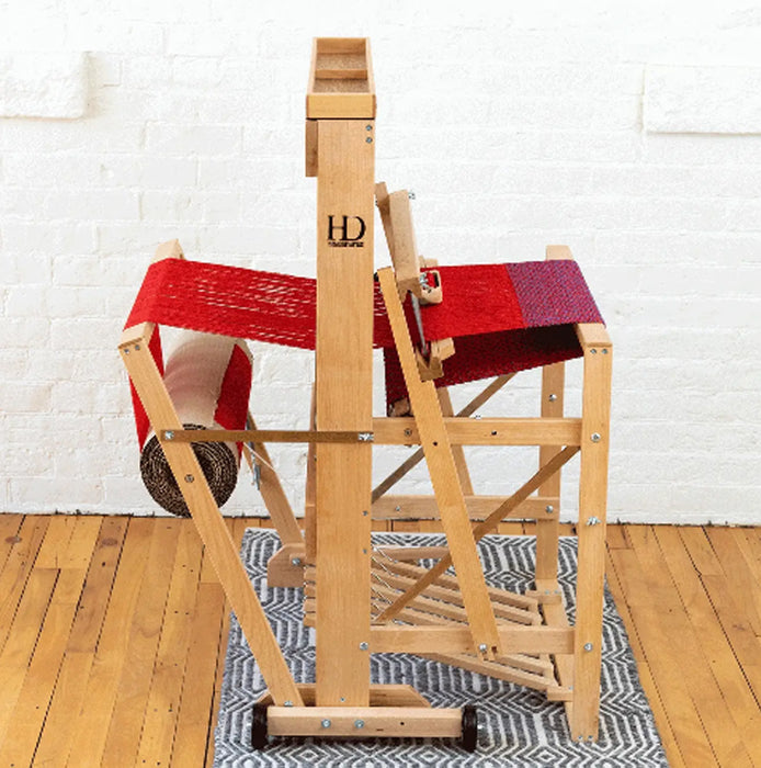 Side view of Harrisville Designs 4-shaft floor loom weaving red cloth