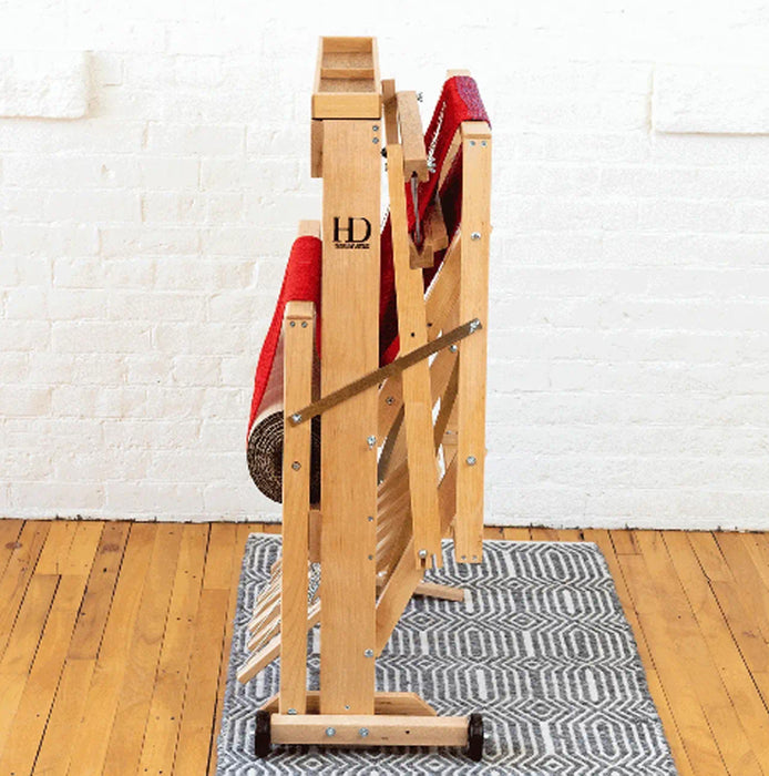 Side angle of Harrisville Designs 4-shaft floor loom showing treadles and frame in a folded position