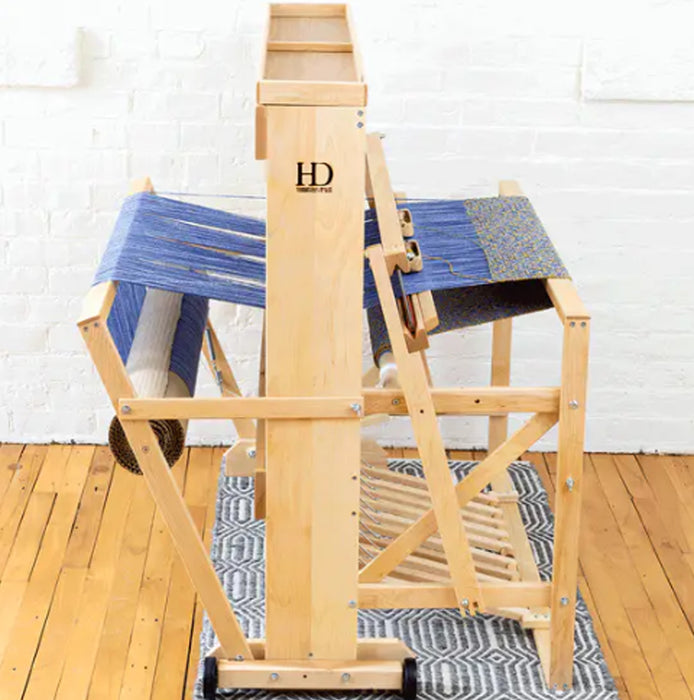 Side view of Harrisville Designs floor loom weaving blue cloth