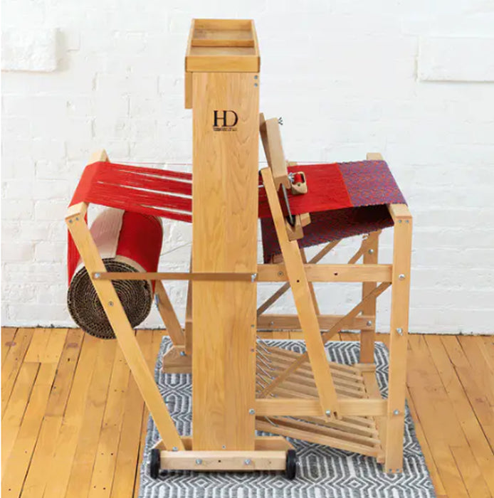 Side view of Harrisville Designs floor loom weaving red cloth
