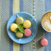 Close-up of Mayu cotton and linen placemat with coffee and colorful macarons – Tisse et File