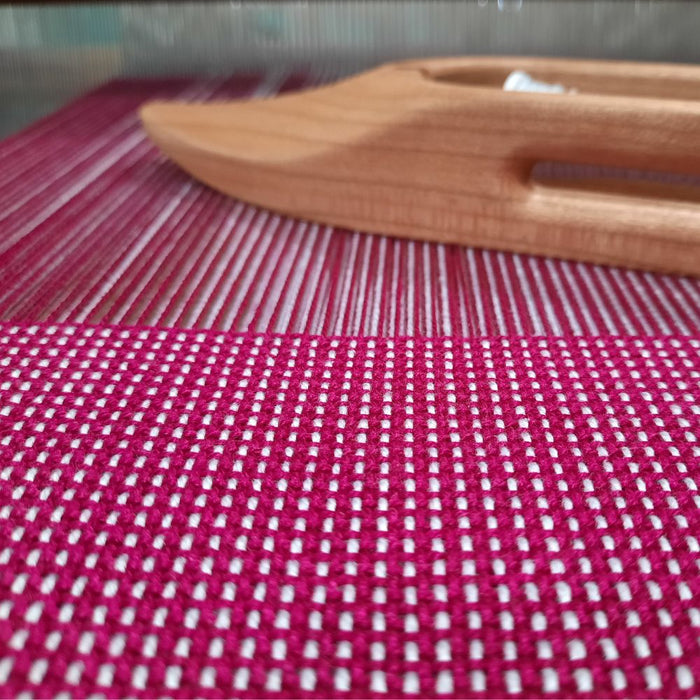 Double weave sample in progress with wooden shuttle on a four-shaft loom