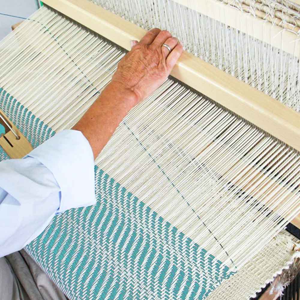 Hand weaving on a loom with visible warp and weft – weaving tools and textile equipment