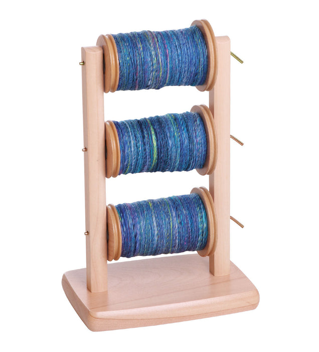 Ashford spinning wheel lazy kate with multiple bobbins filled with yarn